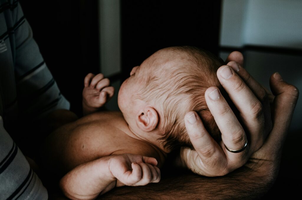 drinking as a new mom, parent holding newborn baby